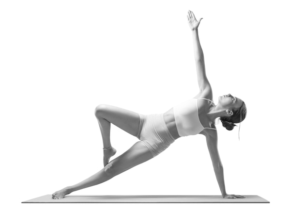 Giovane donna sportiva che fa pratica di yoga. isolato su uno sfondo bianco. il concetto di uno stile di vita sano e di un equilibrio naturale tra corpo e sviluppo mentale. pilates, stretching.