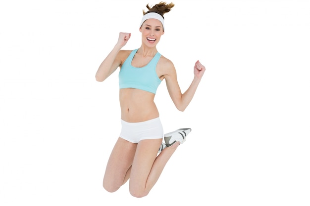 Sporty young woman jumping smiling cheerfully at camera