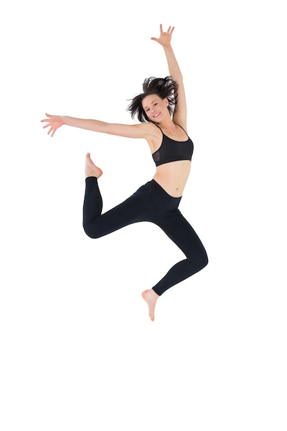 Sporty young woman jumping over white background