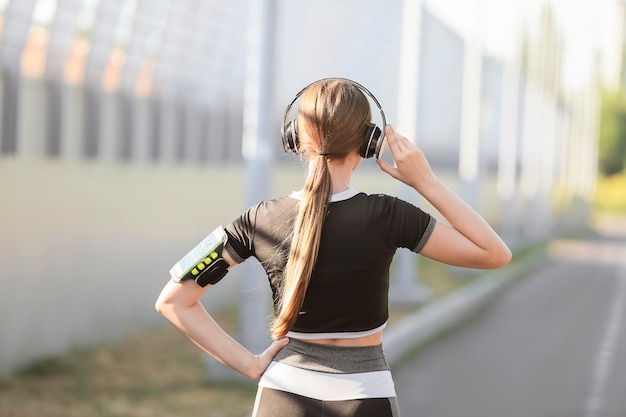 Photo sporty young woman listening to music outdoors