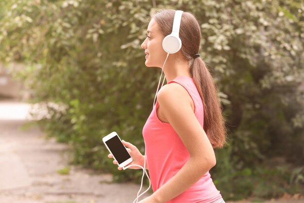 屋外で音楽を聴くスポーティな若い女性