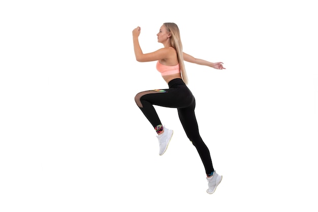 A sporty young woman in a pink top, leggings and sneakers does exercises