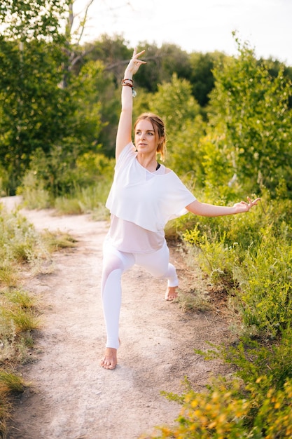 Giovane donna sportiva che pratica yoga nel parco fuori città signora meditativa che si gode la meditazione