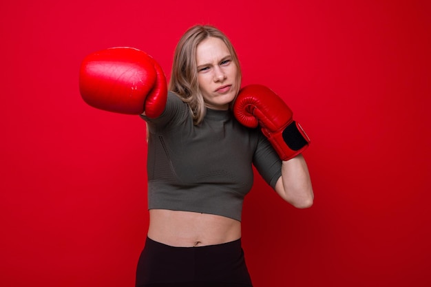 Sporty young woman in red boxing gloves is fooling around