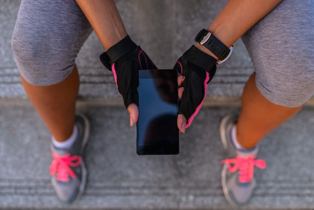 Giovane donna sportiva che per mezzo di un telefono