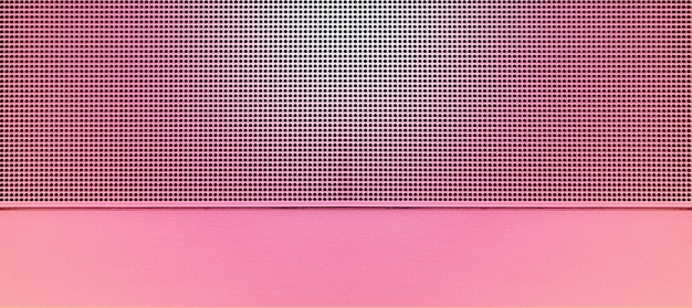 Spot lit perforated pink metal plate. Metal background close-up