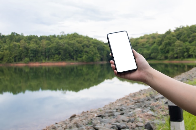 Spot omhoog cellphone op rivieroever met groene aardachtergrond. bedrijfs concept