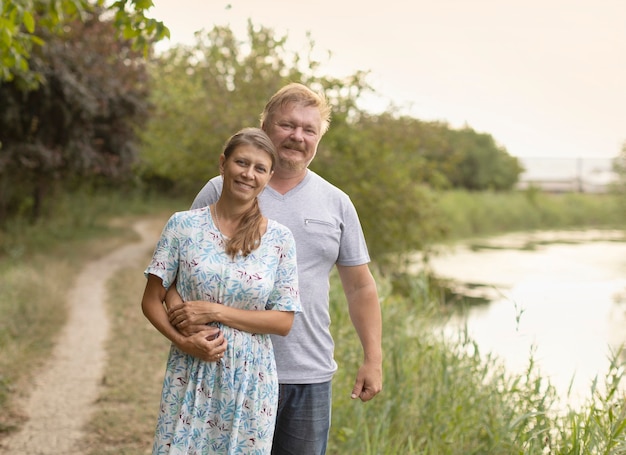 Spouses stand together on the river bank