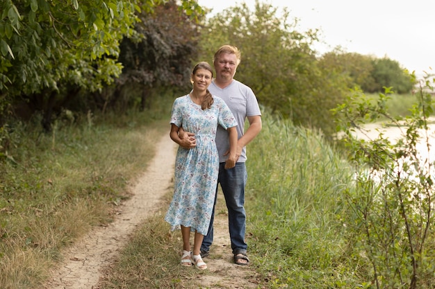 Spouses stand together on the river bank