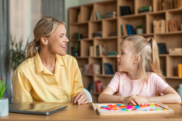 Spraaktraining voor kinderen Professionele vrouwelijke specialistische training met meisje die kinderen juiste articulatie-oefeningen leert