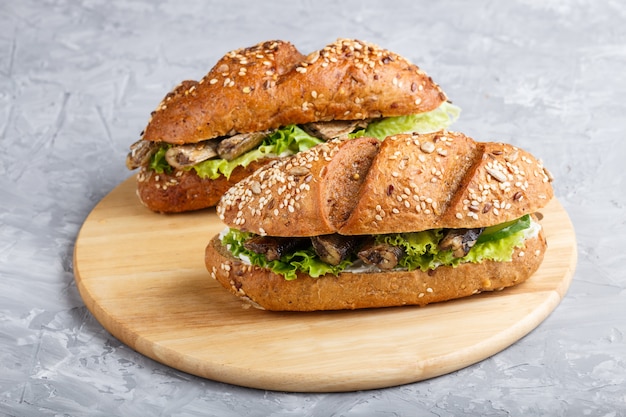 Sprats sandwiches with lettuce and cream cheese on wooden board on a gray concrete background