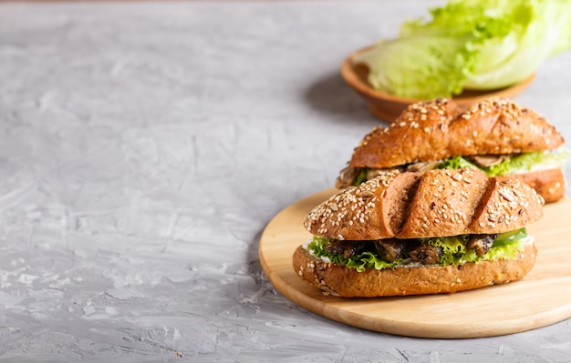 Sprats sandwiches with lettuce and cream cheese on wooden board