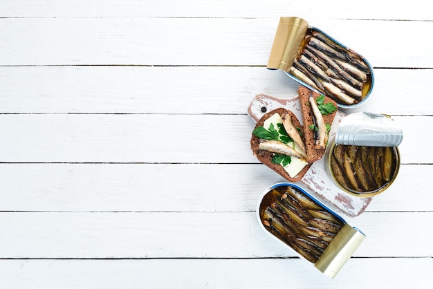 Sprats with oil in a jar on a white wooden background top view free copy space