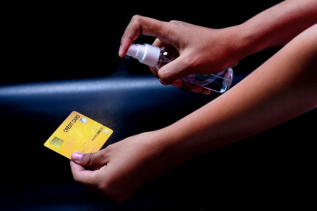 Spray bij de hand en creditcard die laat zien hoe ziektekiemen te vernietigenCovid19