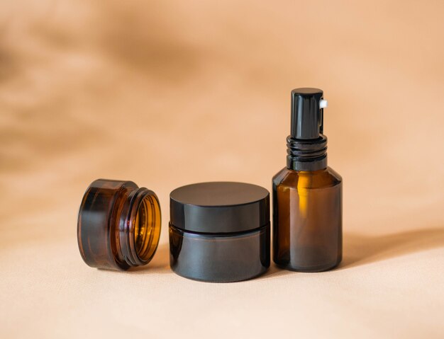 Spray bottle and 2 cosmetic
jars stand on a beige background