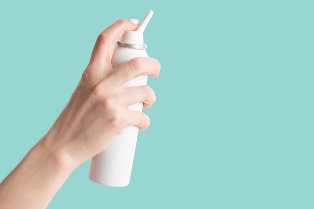 사진 청록색 배경에 격리된 여성의 손에 비강 위생을 위한 염수 스프레이 병
