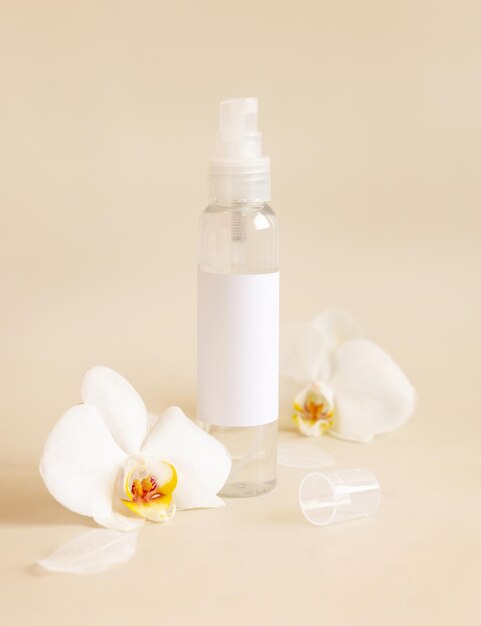 Spray dispenser bottle near white orchid flowers on light beige close up Mockup