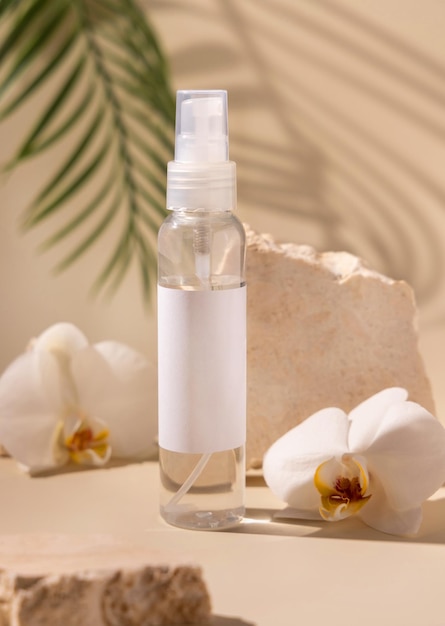 Spray dispenser bottle near white orchid flowers and stones hard shadows close up Mockup