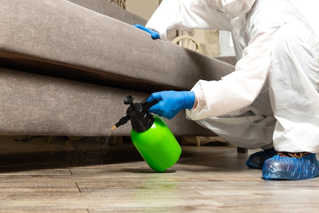 Spray gun with pesticides closeup An exterminator in work clothes sprays pesticides from a spray bottle Fight against insects in apartments and houses Disinsection of premises