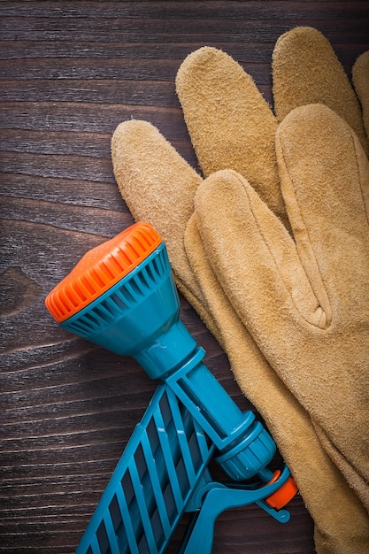 Spray water hose nozzle and leather protective gloves on wooden board gardening concept