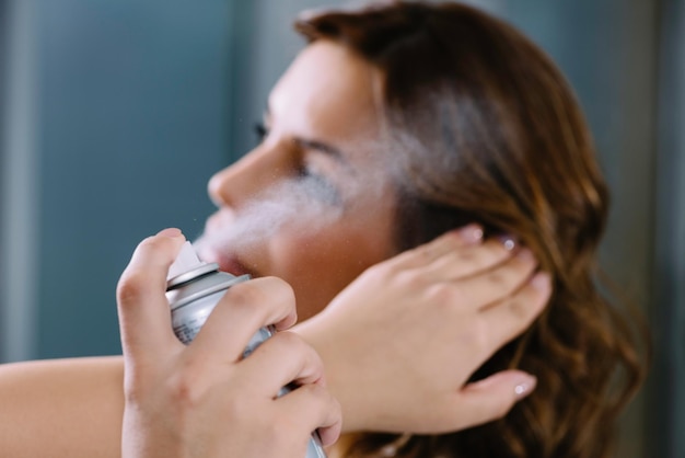 Spraying hair with hair spray in hair salon