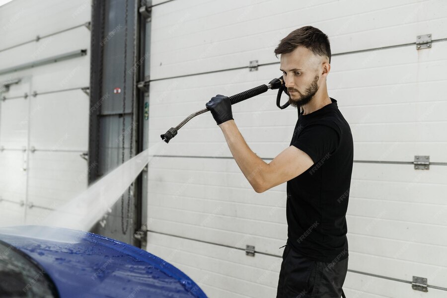Premium Photo Spraying water on car to wash off foam in the garage