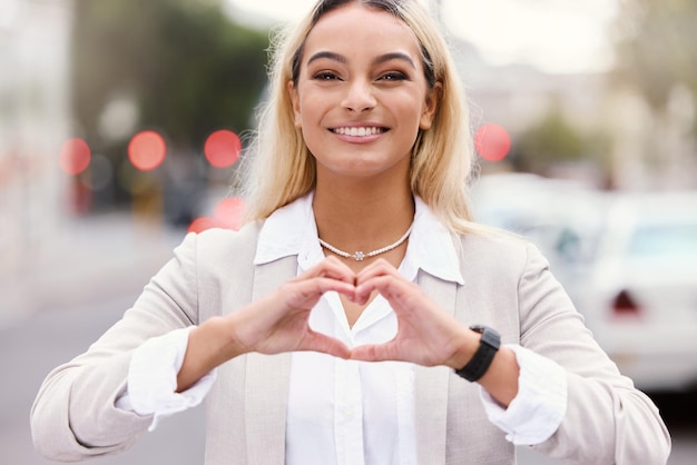 Foto diffondere l'amore. ritratto ritagliato di una giovane donna d'affari attraente che fa una forma a cuore con le mani mentre cammina per la città.