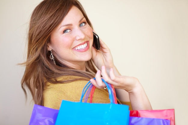 Spread the news the sale is ON Cropped shot of a beautiful young woman talking on her cellphone while holding shopping bags