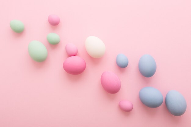 Spreaded pastel colored Easter Eggs on pink background.