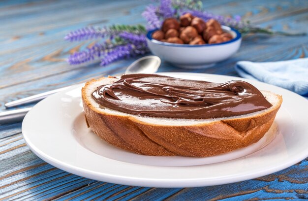 Spreading hazelnut cream on white bread slice, chocolate nut butter on school lunch toast