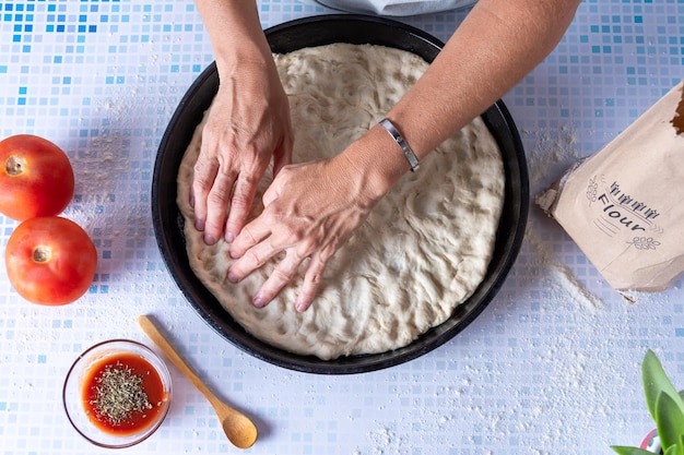 Spreading the pizza dough on the baking dish