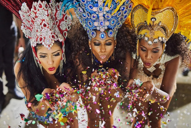 Spreading their magic through the night Shot of samba dancers blowing confetti from their hands while performing in a carnival