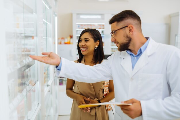 Spreek positiviteit uit. Professionele chemicus die in halve positie staat en naar planken met pillen wijst