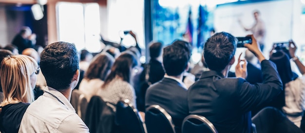 Foto spreker die een toespraak houdt in de conferentiezaal bij het achteraanzicht van een zakelijk evenement van onherkenbare mensen in aud