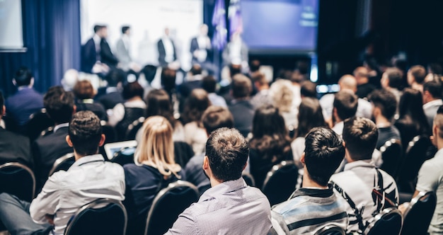 Spreker die een toespraak houdt in de conferentiezaal bij het achteraanzicht van een zakelijk evenement van onherkenbare mensen in aud