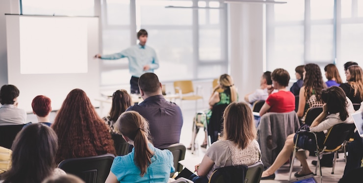 Foto spreker geeft een lezing op zakelijke bijeenkomst achteraanzicht van niet-herkende deelnemer in publiek