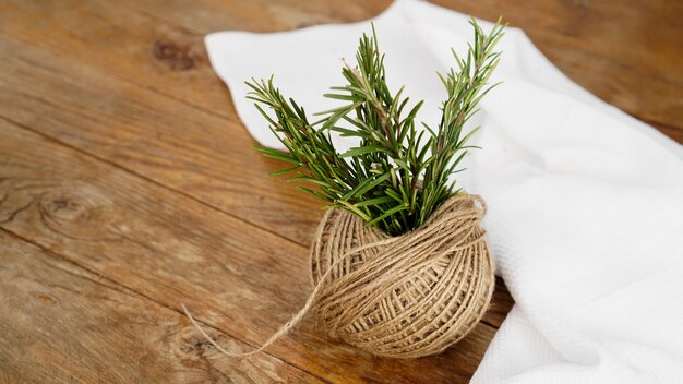 Sprigs of rosemary and skeins of jute rope on a wooden board for cutting