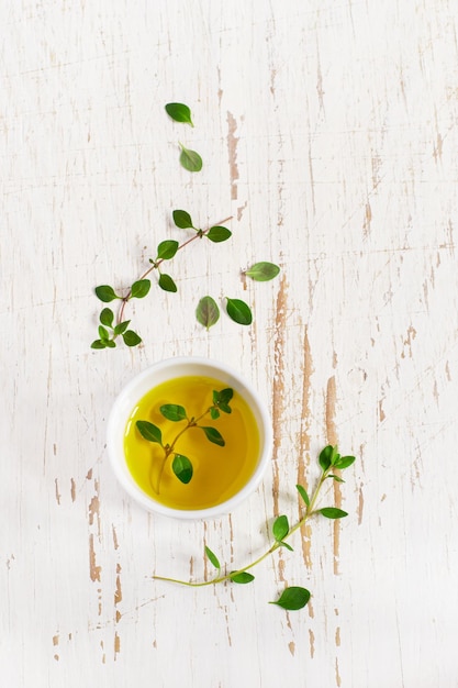 Sprigs of thyme and olive oil on a white Shabby background, top view.