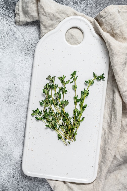 Sprigs of thyme on a white cutting Board.