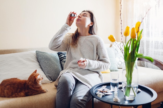 Allergia primaverile donna che usa gocce nasali contro l'allergia stagionale e prende pillole a casa sanità e medicina