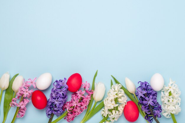 Spring background with multicolored easter eggs and hyacinths on blue. Easter concept. Copy space