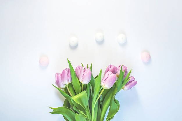 メレンゲクッキーと柔らかな白い背景の上の春の美しいチューリップの花。母の日、グリーティングカードのお祝いの装飾的な花の構成。