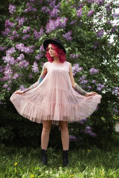 Photo spring beauty portrait of a beautiful girl with red hair in the branches of a blooming lilac.