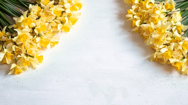 Foto fioriture primaverili, narcisi gialli su un tavolo di legno chiaro.