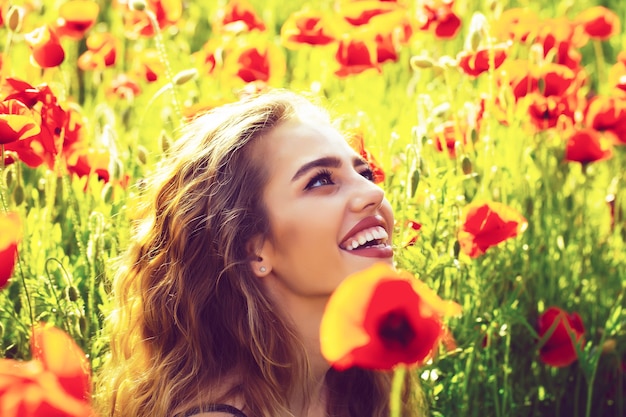 Spring blossom. Facial portrait of sexy female model. Beautiful woman on poppy field with smiling face.