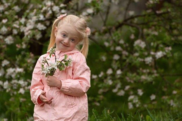 写真 春の花は花の庭で可愛い金の子供のために花の木の近くの小さな女の子の肖像画