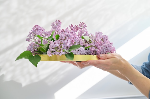 Spring bouquet of lilac flowers on round golden tray