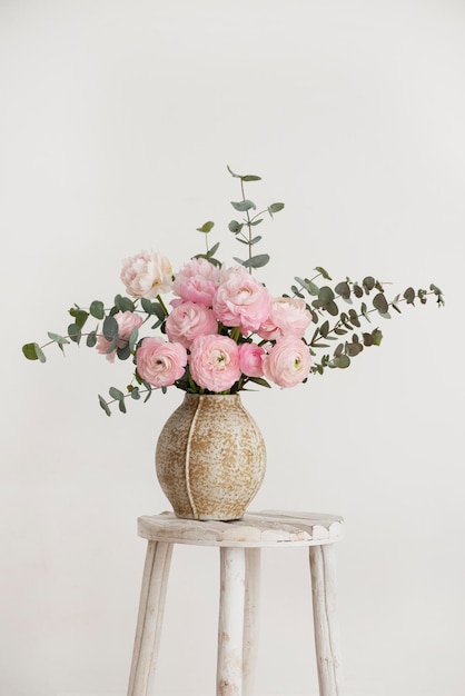 Spring bouquet of peonies and ranunculus in a beige vase selective focus image