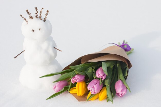 A spring bouquet of tulips next to a snowman International Womens Day on March 8 greeting card