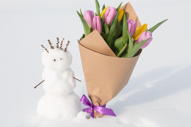 A spring bouquet of tulips next to a snowman International Womens Day on March 8 greeting card